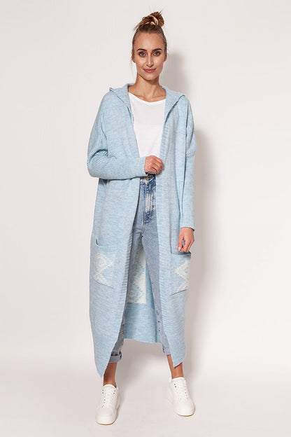 Stunning MKM extended cut cardigan in light blue, elegantly worn by a model, featuring a cozy hood and generous pockets for a luxurious style.