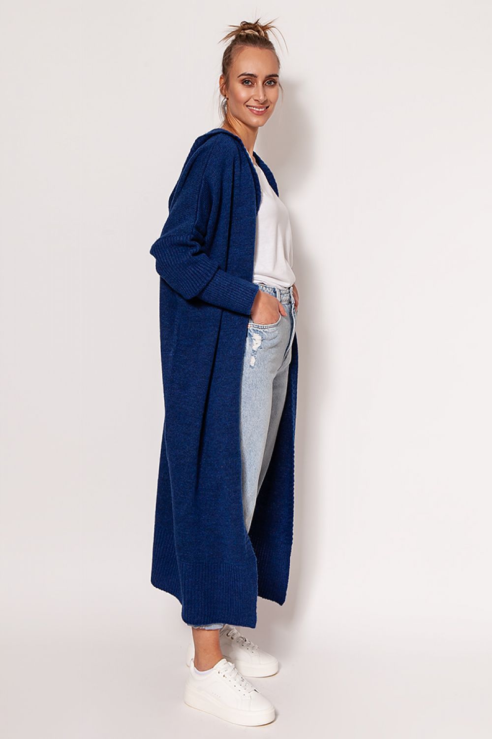 Stylish woman in a navy MKM extended cut cardigan with hood, paired with relaxed fit jeans and white footwear, exuding casual luxury.