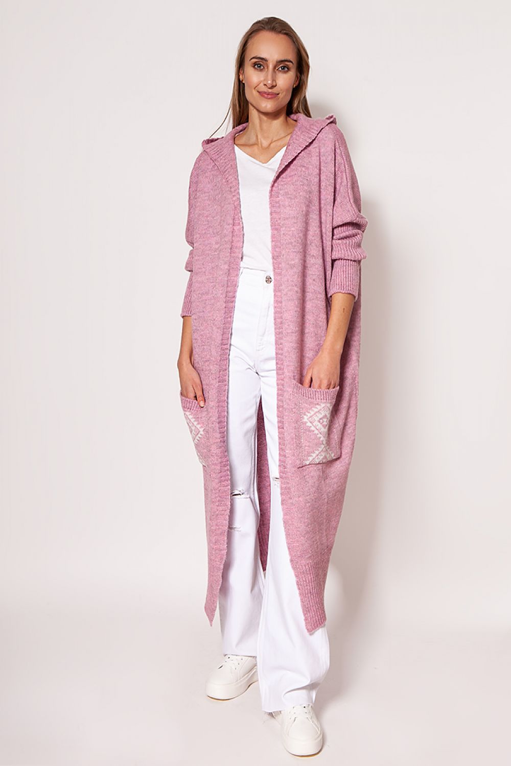 Graceful woman in a soft pink MKM extended cut cardigan, complemented with white trousers and chic sneakers, ideal for a luxurious yet casual look.