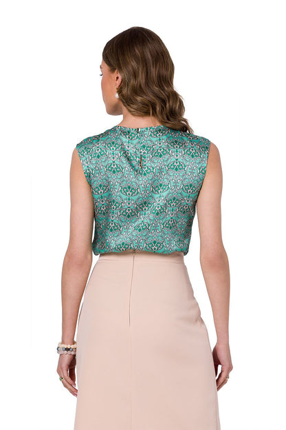 Back view of the Stylove sleeveless blouse in an intricate green pattern, styled with a beige skirt, perfect for a polished professional look.