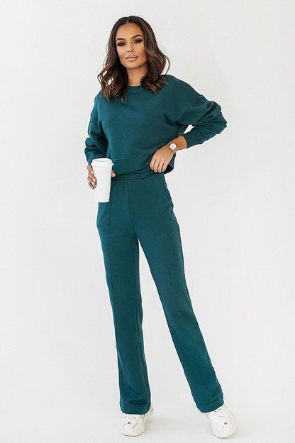 Fashionable model in IVON cotton blend sweatpants, highlighting a sophisticated casual outfit with a relaxed fit top and beverage, perfect for modern elegance.