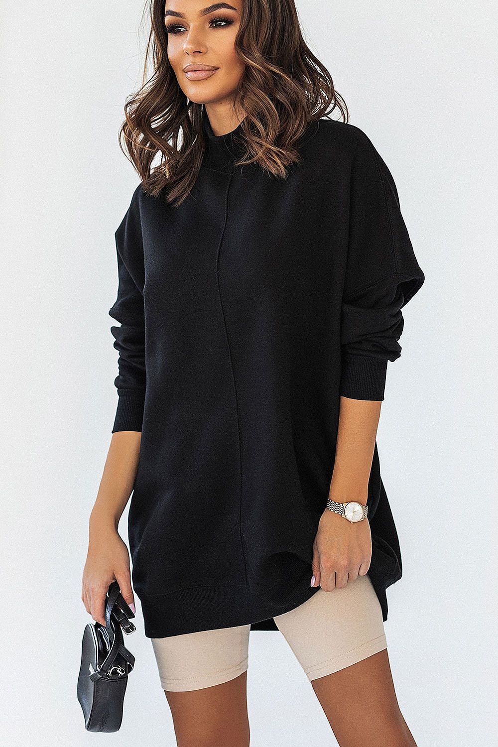 Chic woman dressed in IVON beige cycling shorts and a black oversized sweatshirt, exuding luxury and comfort in modern fashion.