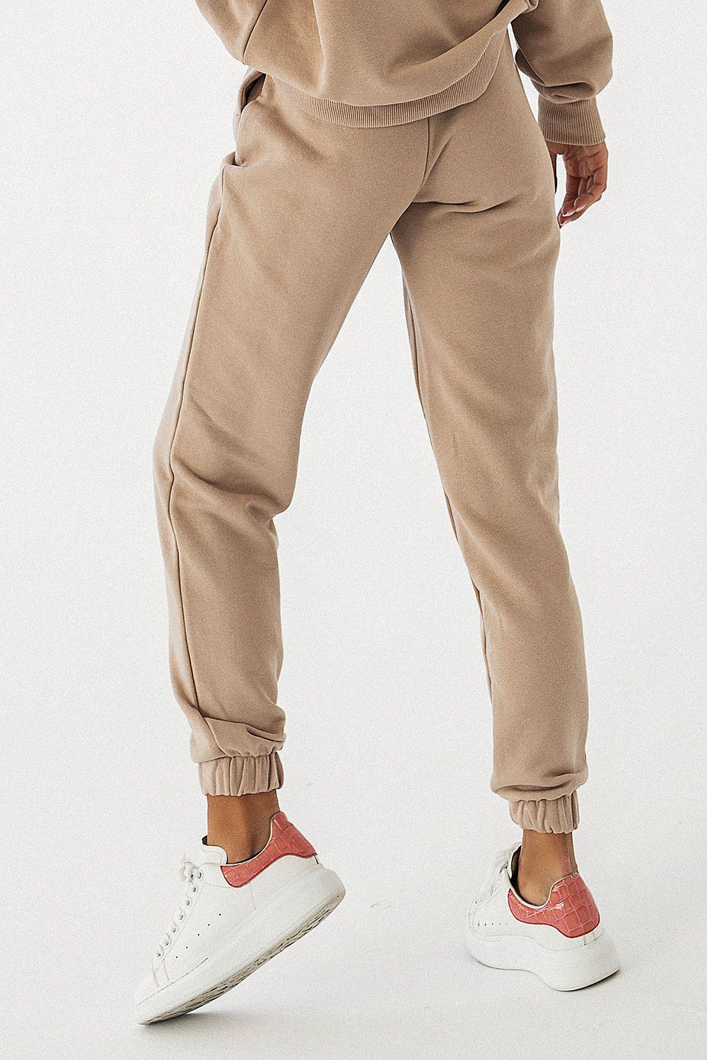 Elegant and luxurious IVON joggers in soft beige with a drawstring and elastic waistband, showcased with stylish white sneakers.
