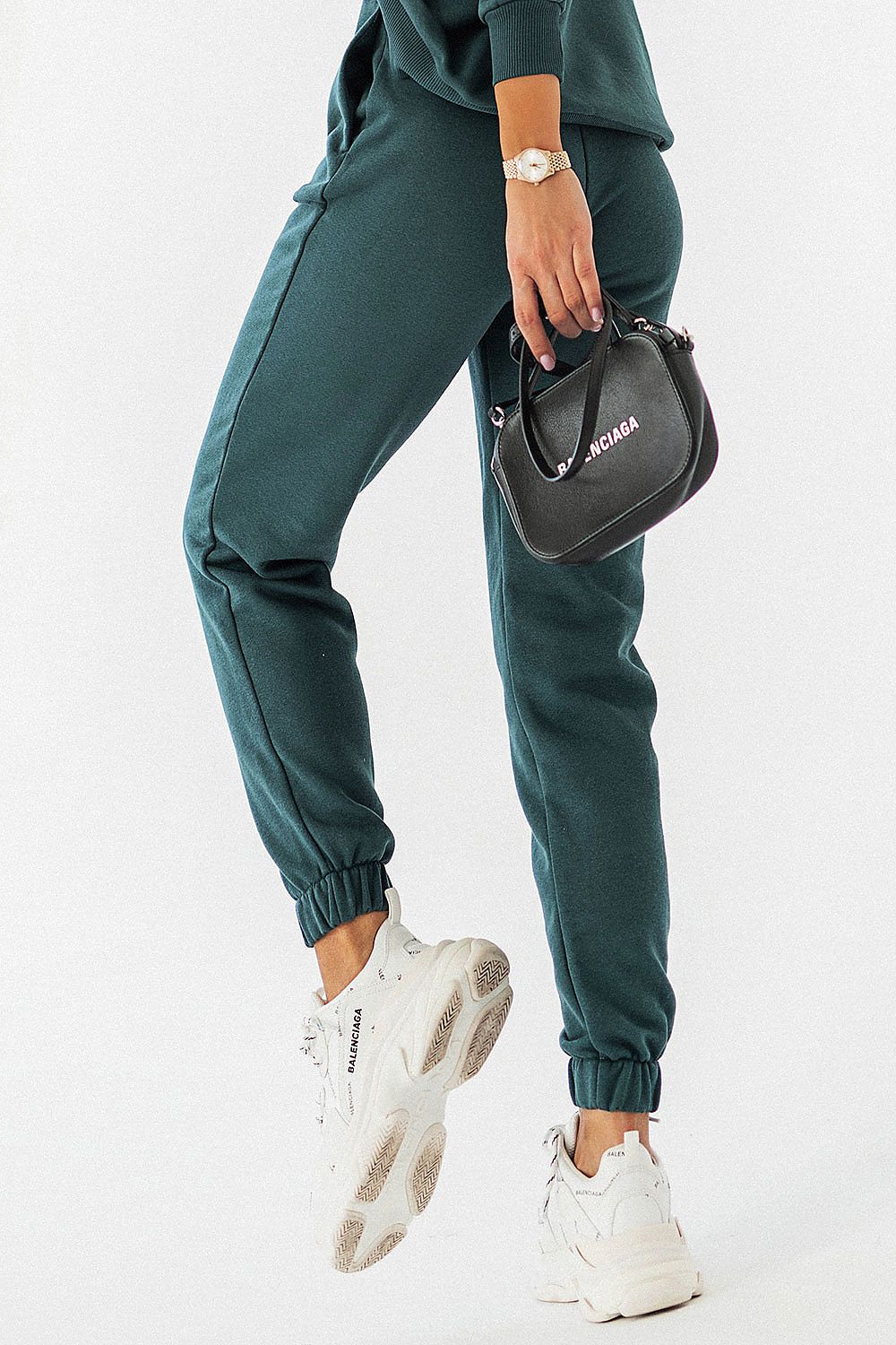 Sophisticated IVON joggers in dark green, highlighted by stylish white sneakers and a designer handbag, demonstrating elegance and comfort.