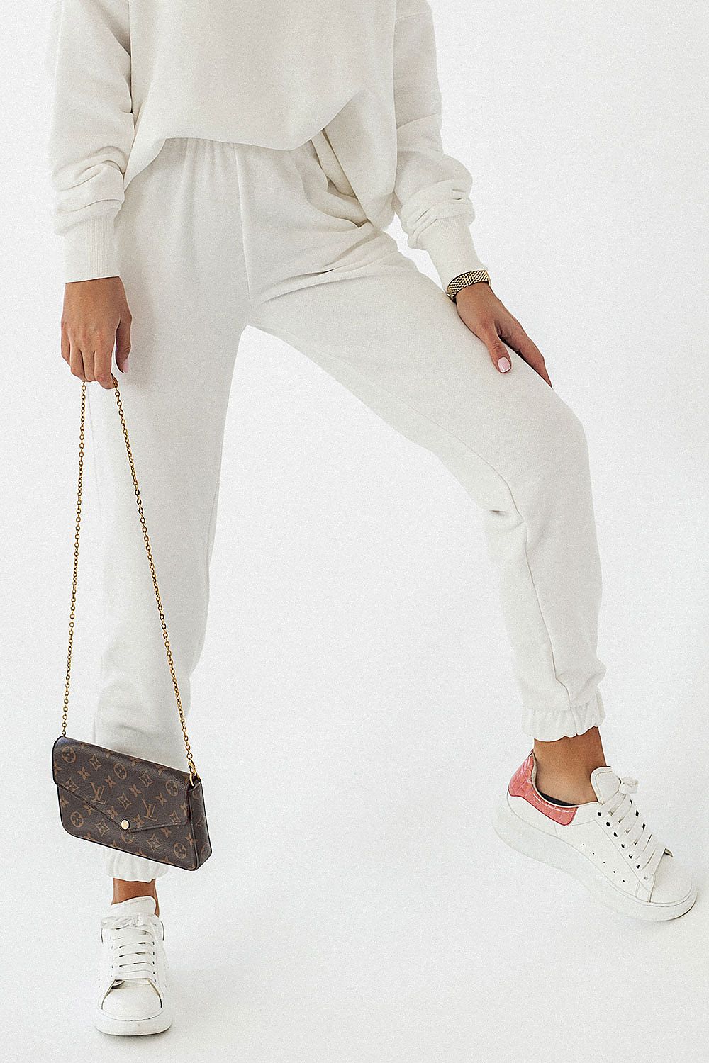 Woman wearing luxury cotton blend joggers IVON in white, paired with a matching sweatshirt and white sneakers, showcasing a chic and comfortable outfit for casual occasions.