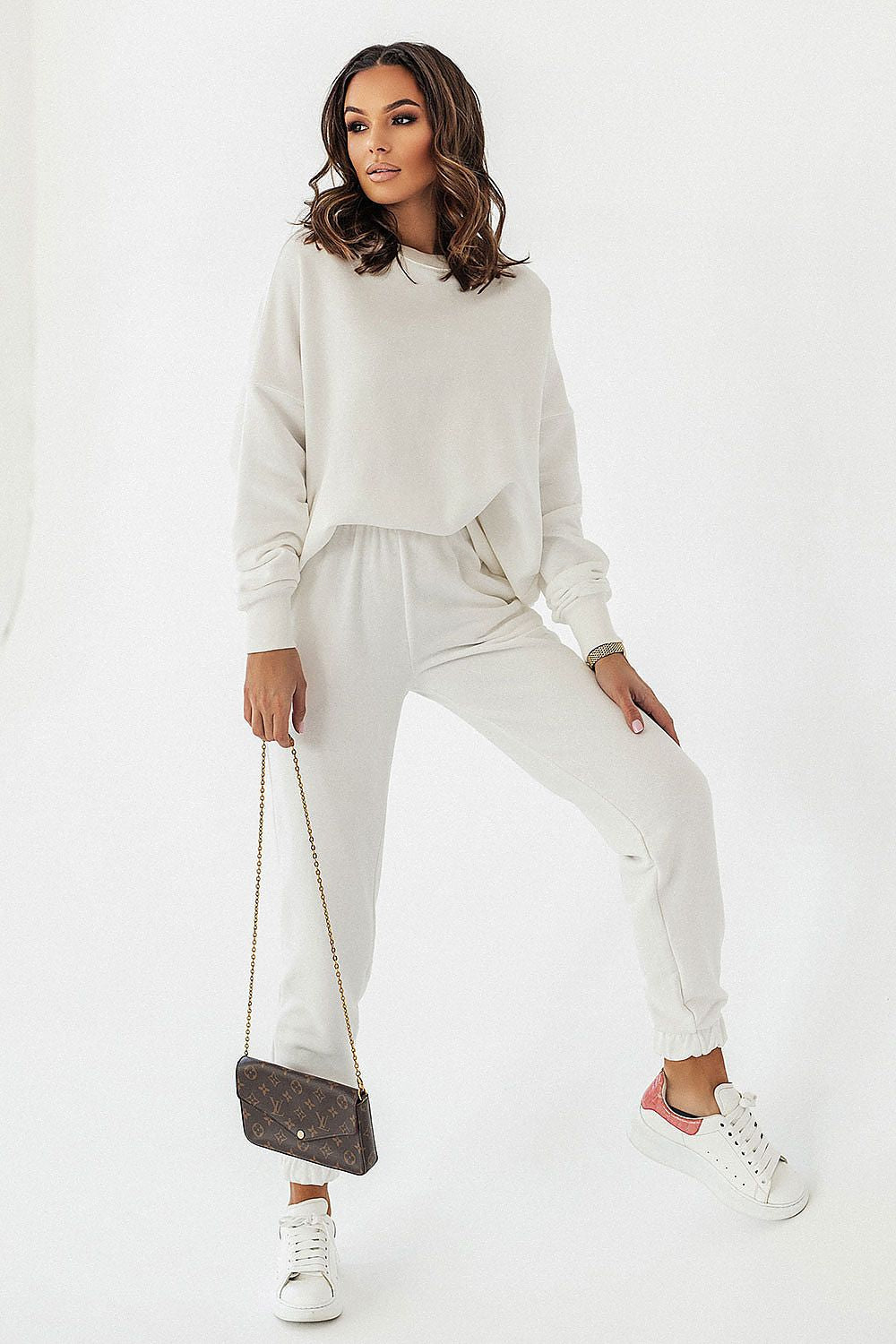 Chic presentation of a model in an off-white IVON oversized sweatshirt and joggers, accessorised with a designer bag, highlighting the perfect blend of style and leisure.