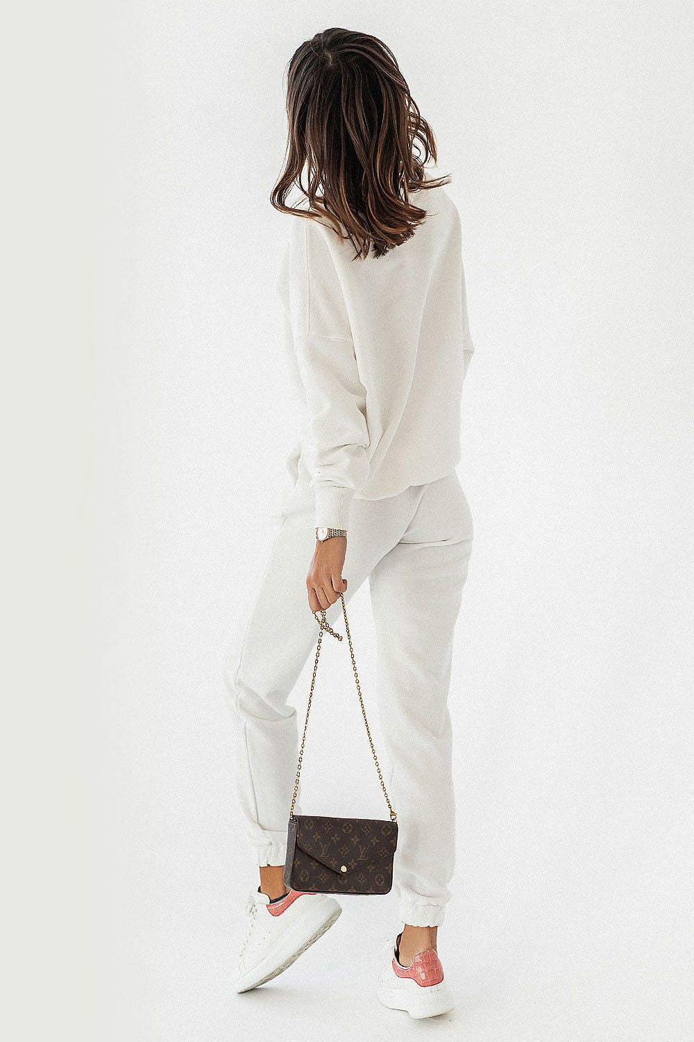 Elegant female model showcasing the IVON Oversized Sweatshirt in luxurious white, paired with joggers, against a minimalist backdrop.