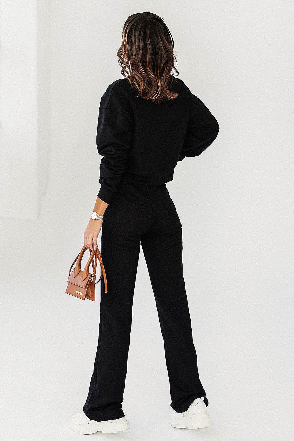 Rear view of a chic woman in IVON black sweatshirt and pants, highlighting the elegant silhouette and craftsmanship.
