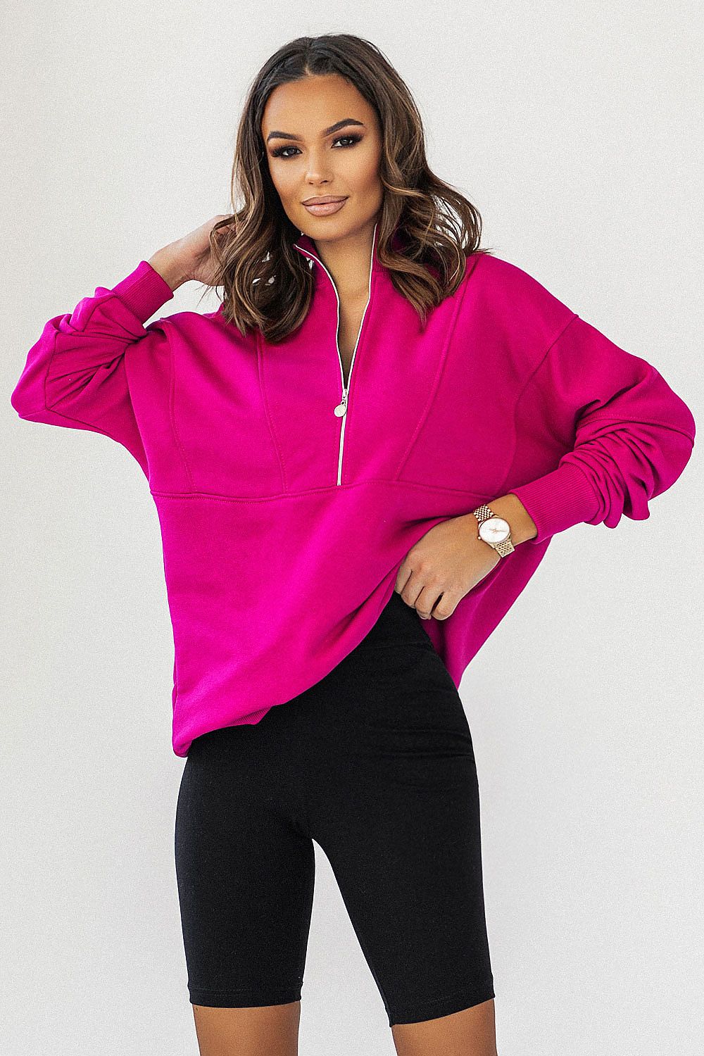 Luxury IVON oversized sweatshirt in vibrant pink with striking collar and adjustable zipper, styled with black cycling shorts, exuding elegance and comfort.