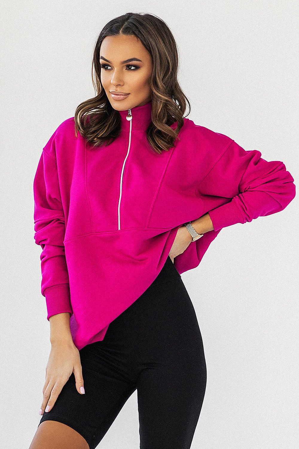 Sophisticated IVON oversized sweatshirt in bold pink, featuring an adjustable collar zipper, elegantly styled with black cycling shorts, perfect for upscale casual wear.