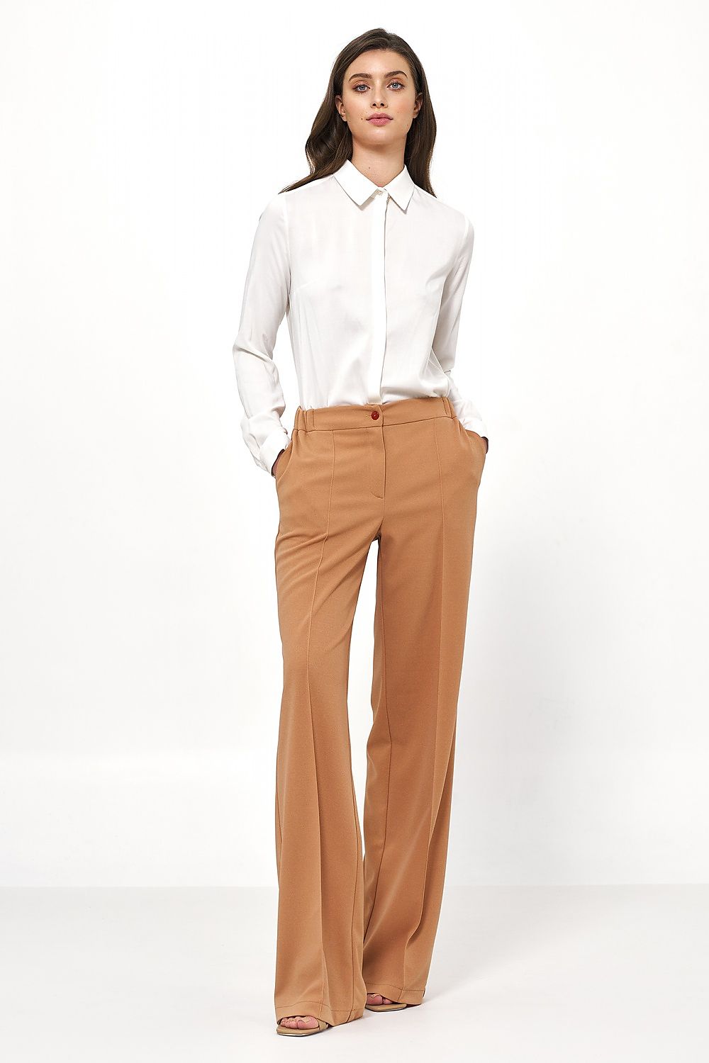 Full-body view of a model wearing a white blouse and stylish beige trousers, showcasing office elegance by Nife.