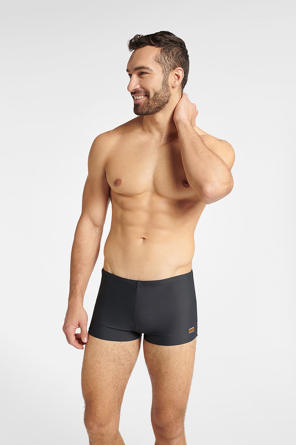 A male model showcasing Henderson Men's GULF Swim Trunks in a classic grey shade, featuring a body-conforming design and elastic waistband, exuding sophistication and style.