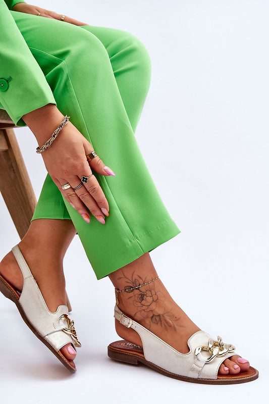 Stylish luxury women's natural leather sandals with chain embellishment by Step in Style, displayed in elegant pose while paired with bright green trousers, highlighting comfort and sophistication.