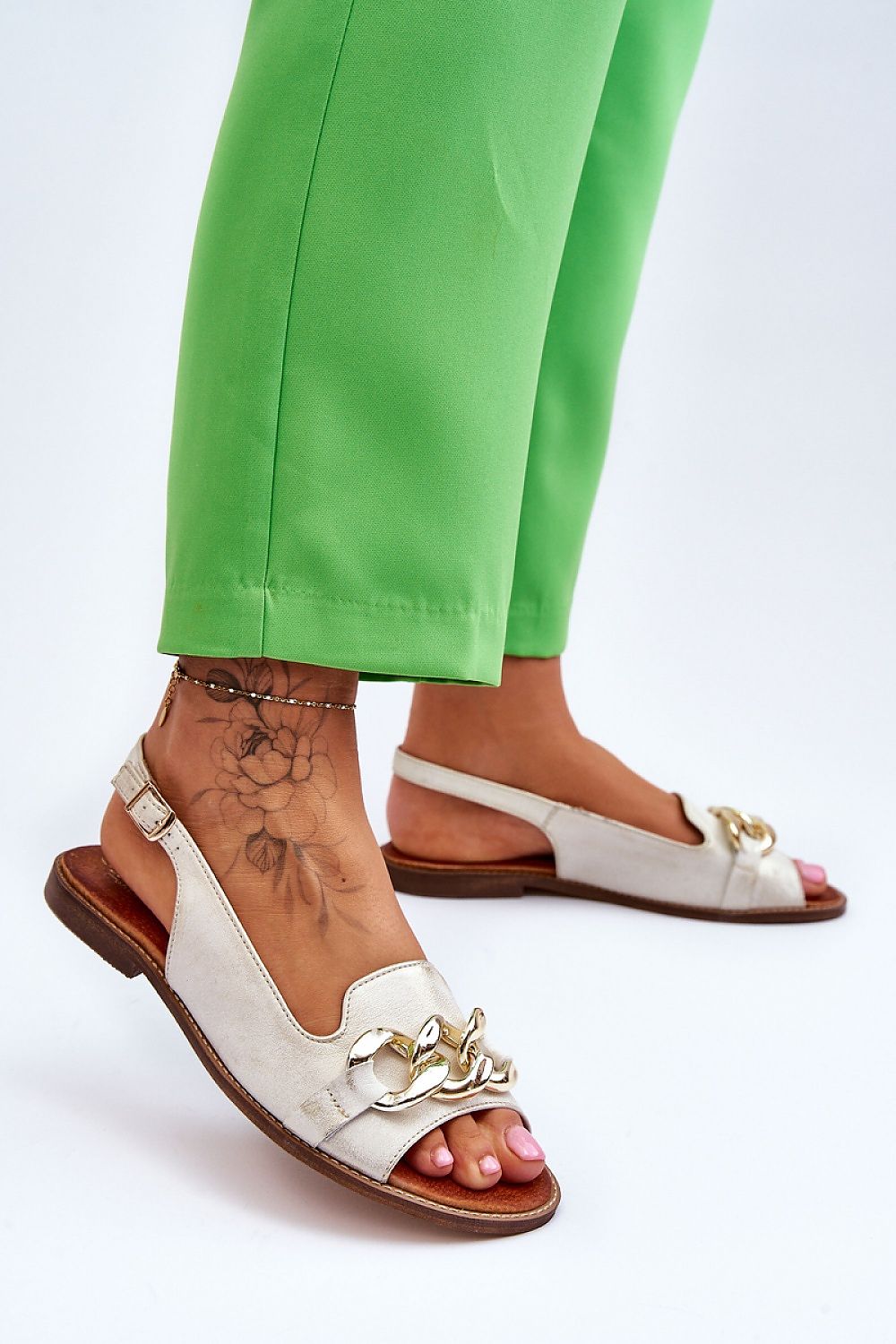 Luxury women's natural leather sandals by Step in Style, featuring adjustable strap, chain detail, and set on a 1.5 cm flat heel, styled with green trousers.