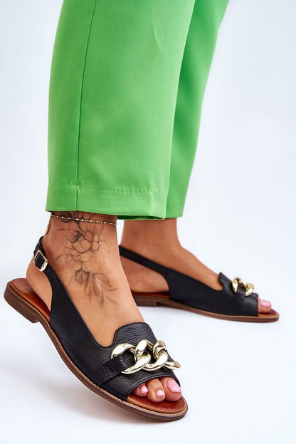 Elegant black natural leather sandals by Step in Style, showcasing chain detail and adjustable strap, paired with vibrant green trousers.