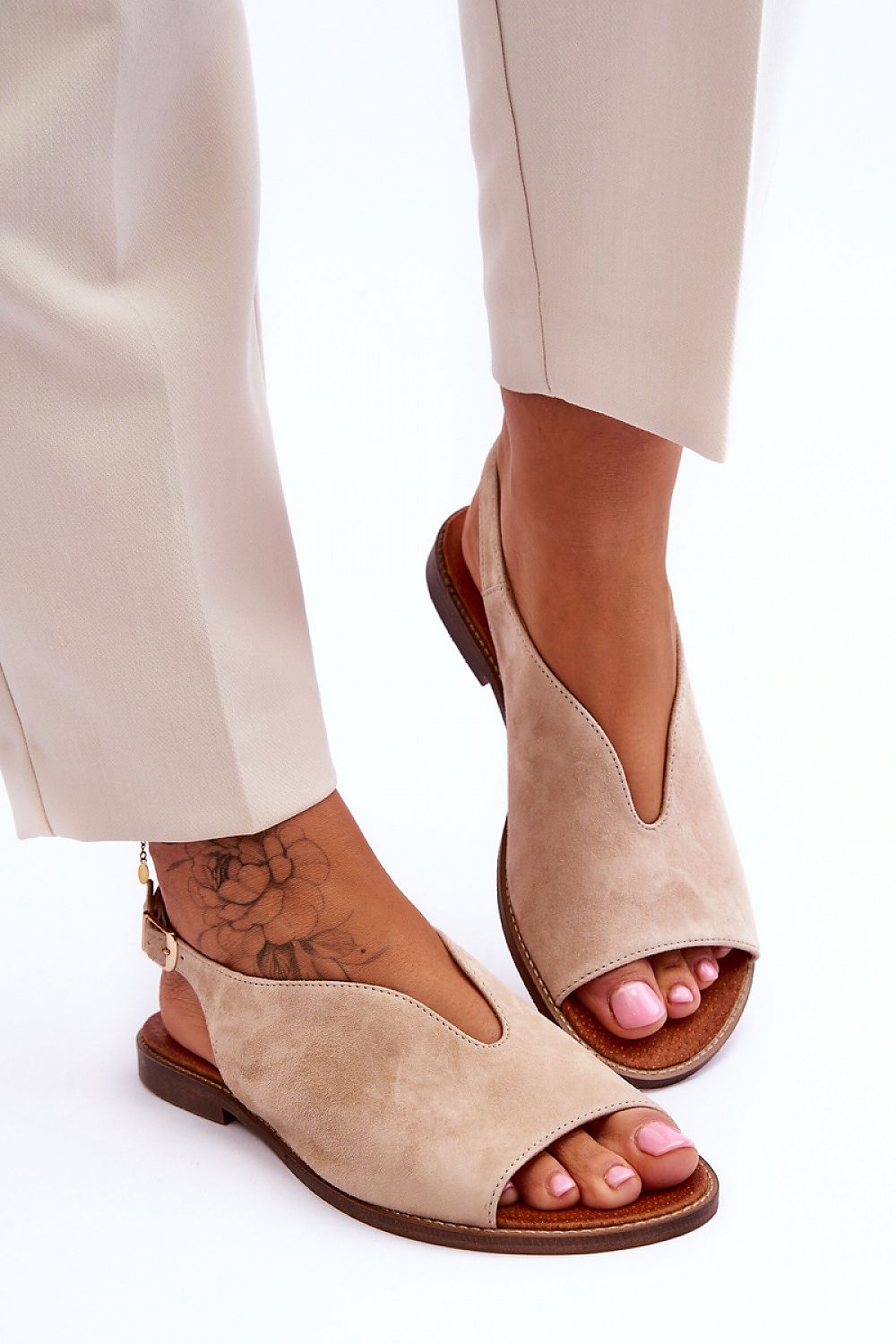 Sophisticated flat heel leather sandals by Step in Style, highlighting their unique design with an adjustable buckle, presented in a refined outfit with a fashionable leg display.