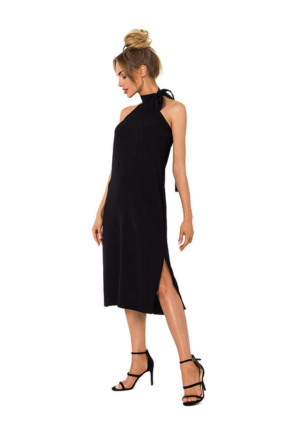 A model elegantly poses in a chic black halter neck crepe daydress with an open back, showcasing its versatility for day and evening wear, by Moe.