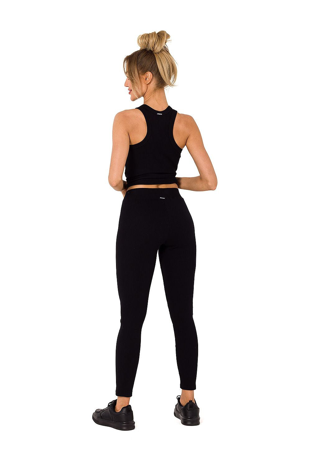 Back view of a stylish model wearing black Moe ribbed knit leggings and tank top, highlighting comfort and fashionable design.