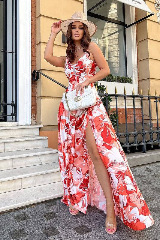 Sophisticated floral satin long dress with slit and fitted waist by Bicotone, model posing gracefully with a hat and designer handbag on a picturesque staircase.