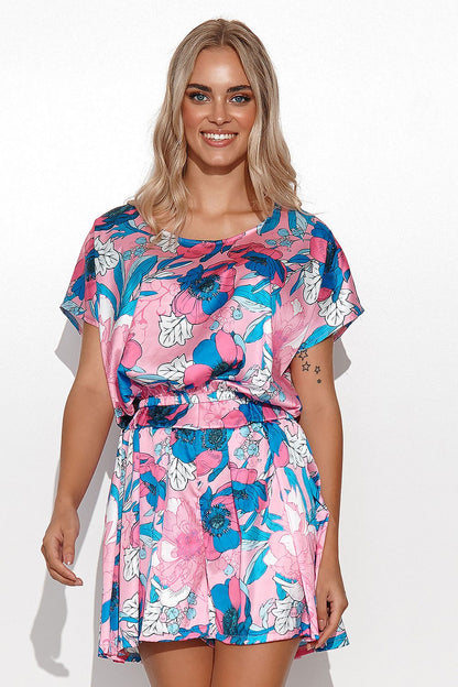 Elegant woman wearing a vibrant floral satin summer set featuring a short blouse and high-waisted shorts by Makadamia, showcasing her stylish look against a light background.