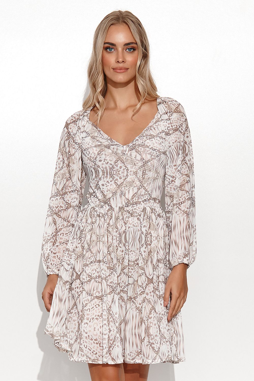 Elegant Makadamia Airy Daydress featuring a girly cut and long sleeves, complemented by a bow detail. Model showcases the dress in a luxurious patterned mesh with a high-cut neckline.