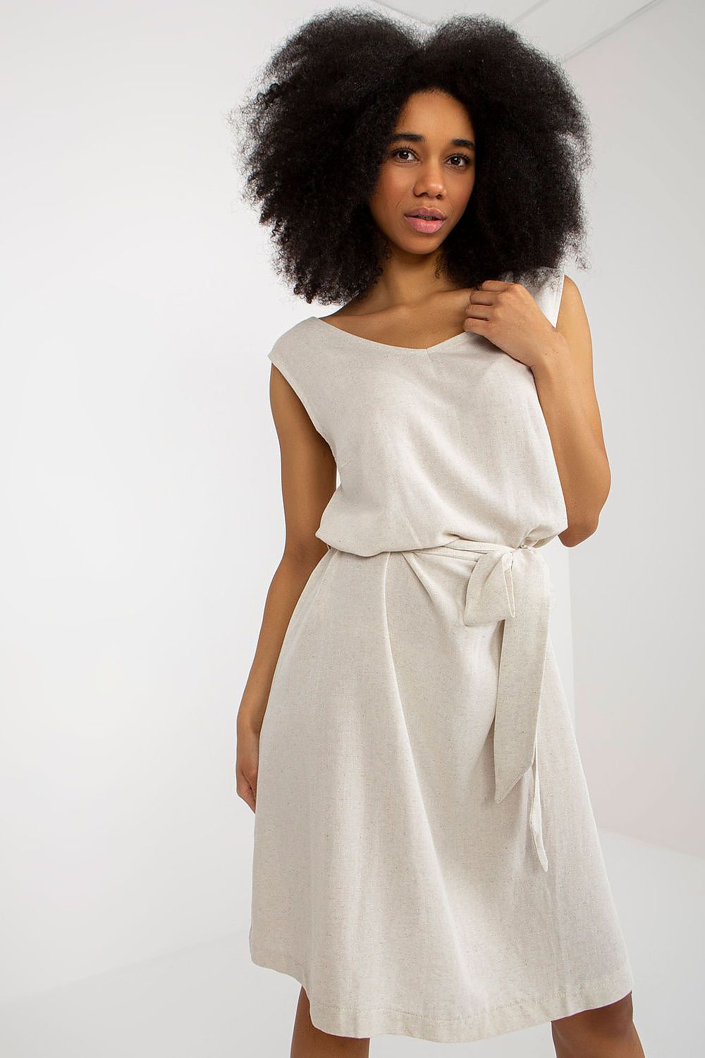 Elegant sleeveless summer dress by Rue Paris featuring a flared cut, v-neckline, and waist tie, modelled gracefully in a neutral tone.