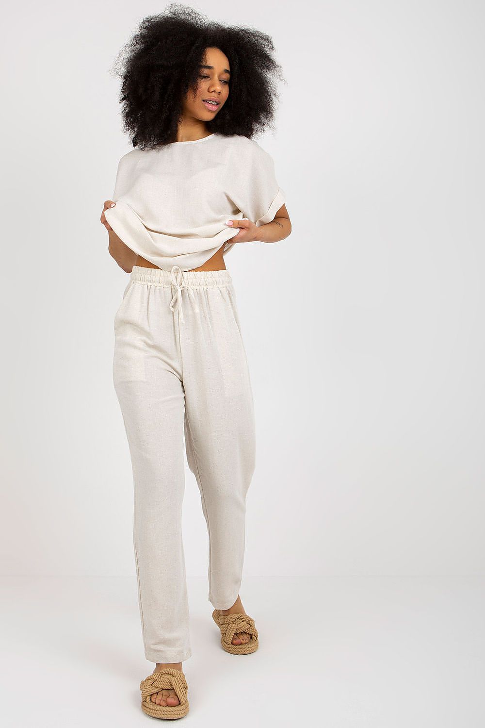 Model showcasing an elegant summer set by Rue Paris, featuring a soft, flowing blouse and stylish long trousers with a tie waist, perfect for chic summer outings.