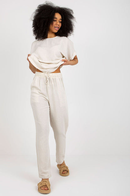 Model showcasing an elegant summer set by Rue Paris, featuring a soft, flowing blouse and stylish long trousers with a tie waist, perfect for chic summer outings.