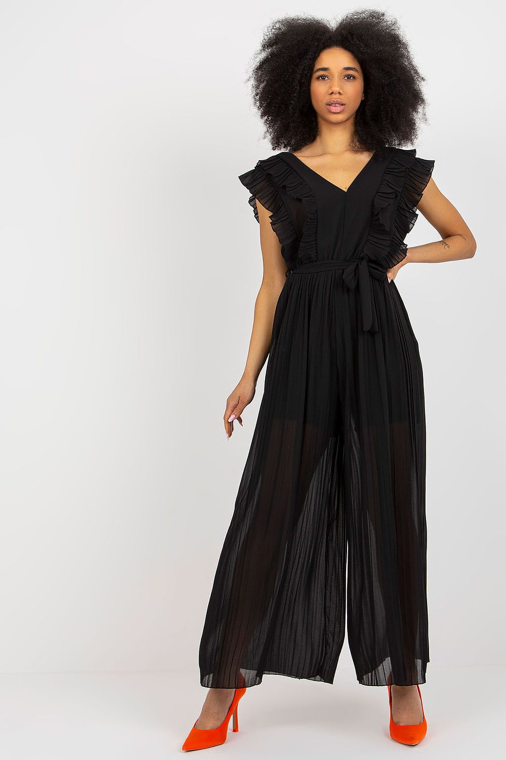 Stylish Och Bella pleated wide leg jumpsuit featuring a v-neckline and waist tie, perfect for elegant occasions, modelled in black with striking orange heels.