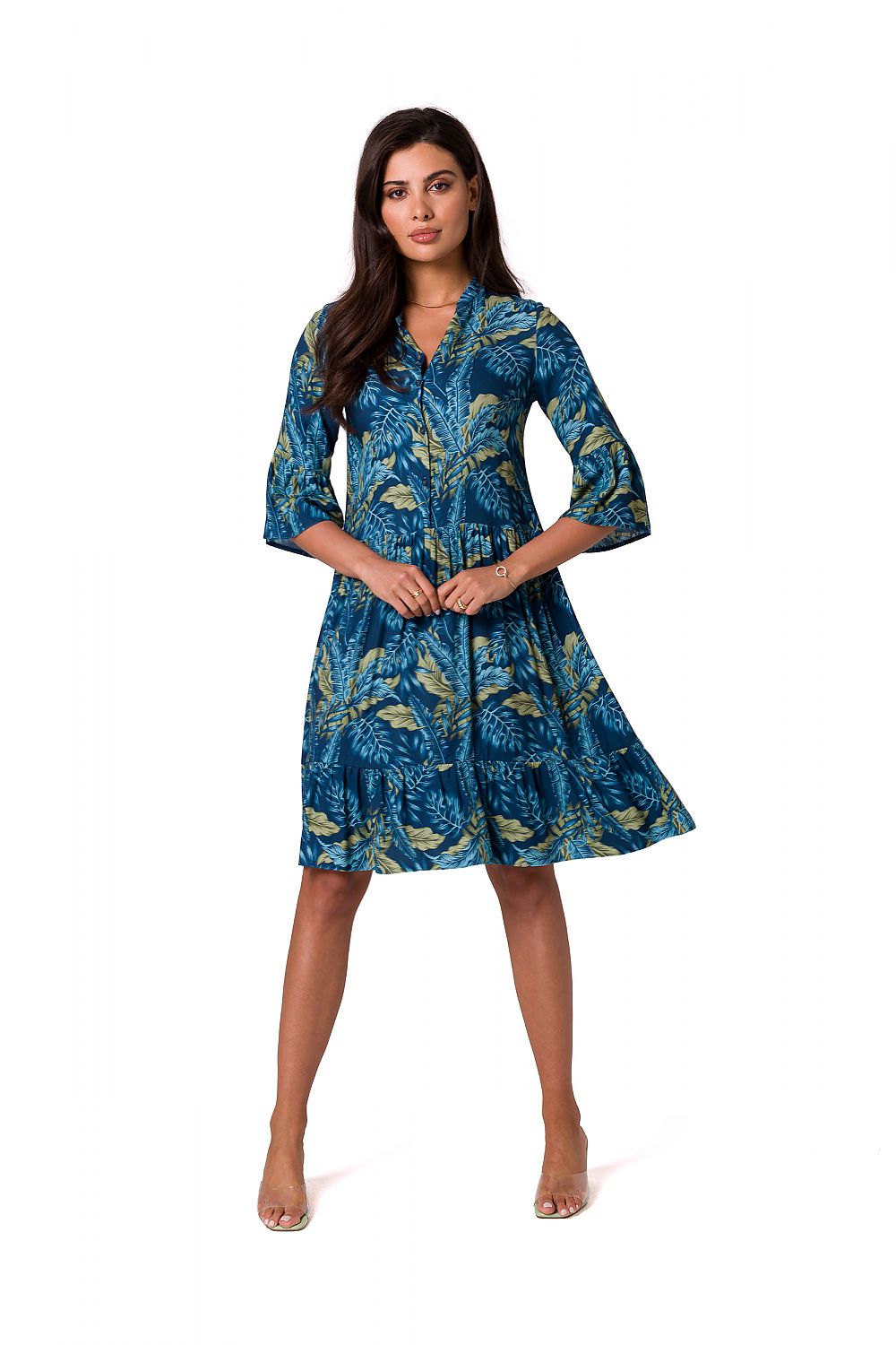 Elegant woman wearing a romantic mismatched daydress by BeWear, showcasing a blue dress with a vibrant leaf pattern and a stylish open neckline.