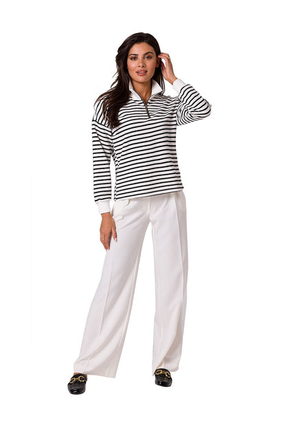 Fashionable model showcasing the BeWear high collar zip sweatshirt paired with white trousers, suitable for chic casual wear in warm weather.