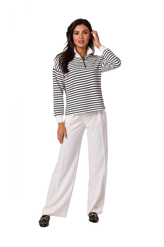 Fashionable model showcasing the BeWear high collar zip sweatshirt paired with white trousers, suitable for chic casual wear in warm weather.