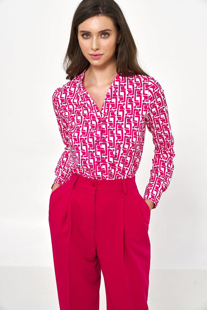 Chic model showcasing an elegant long sleeve button-down shirt by Nife, featuring a striking pink geometric pattern, paired with tailored high-waisted trousers for a sophisticated office look.