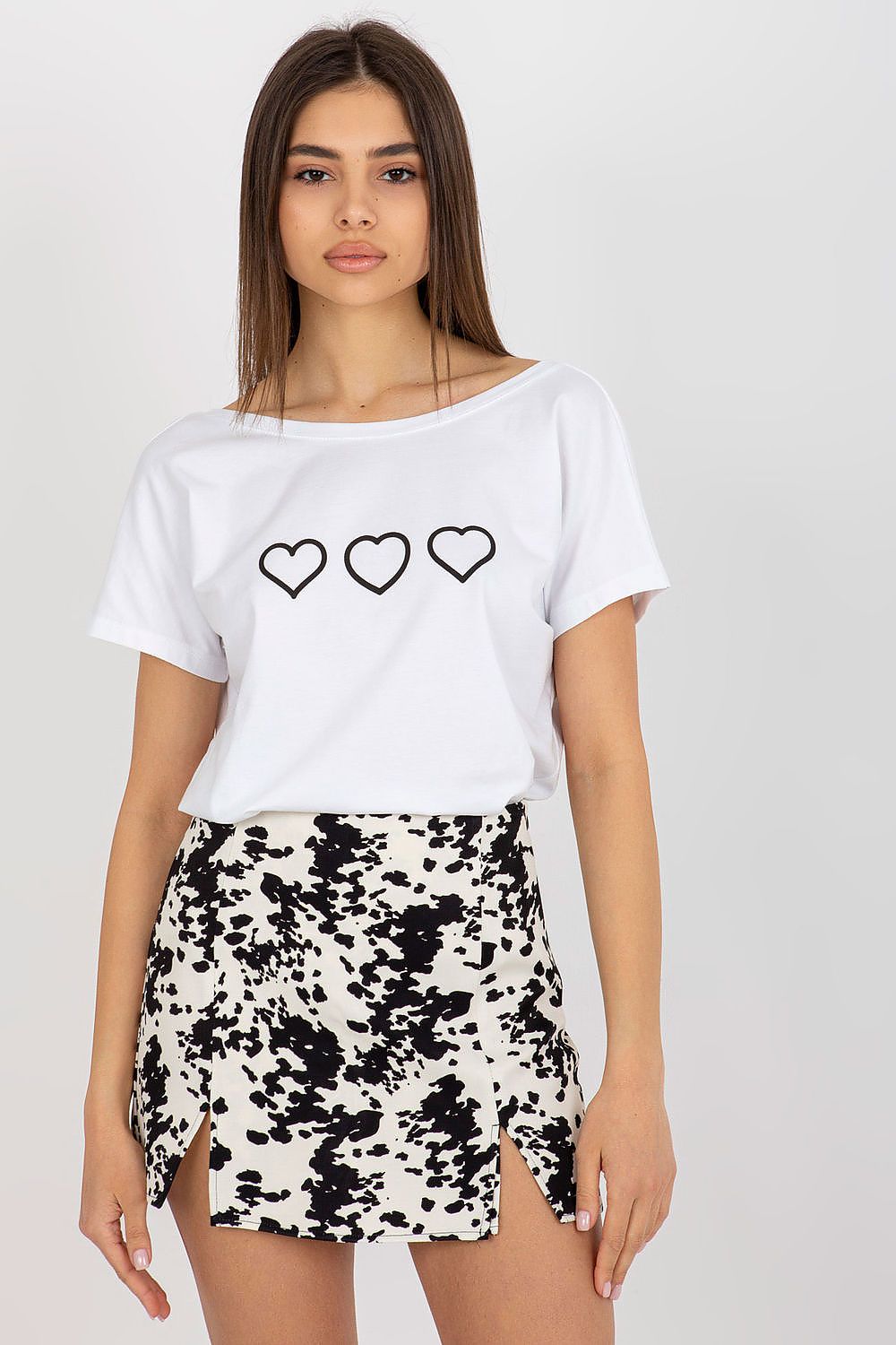 Sophisticated women's straight cut t-shirt by Rue Paris with a boat neckline, showcasing a decorative heart design paired beautifully with a stylish black and white skirt.