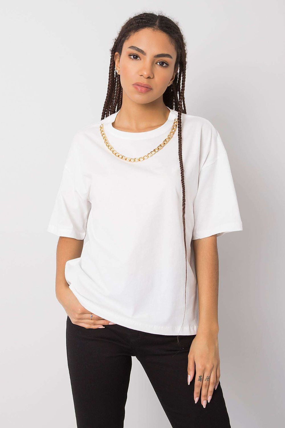 Model wearing a pristine white women's loose-fit t-shirt by Rue Paris with a decorative chain, offering a blend of comfort and high-end fashion.