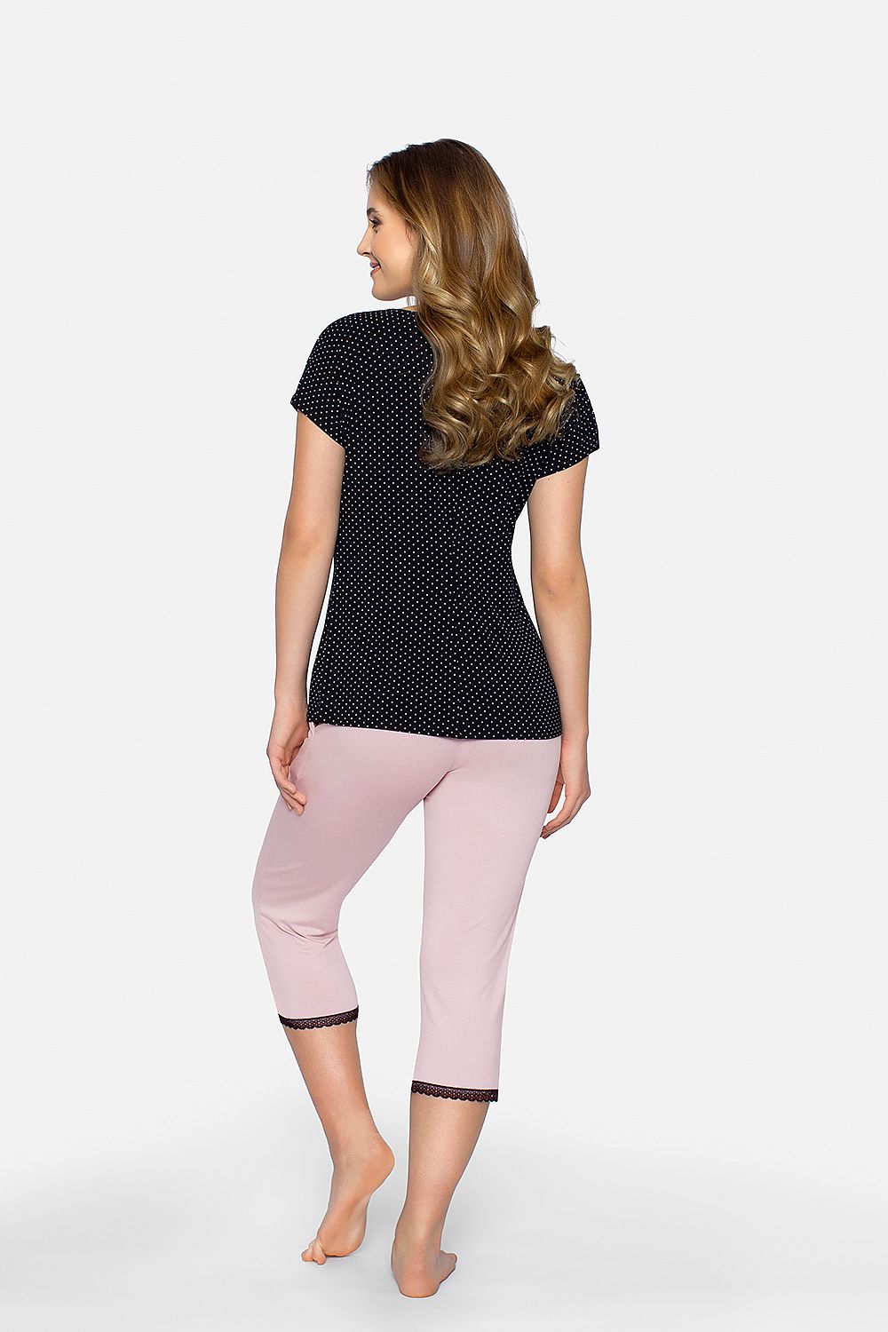 Back view of a woman wearing the Cleo luxury pajama set by Babella, featuring a black patterned blouse and elegant pastel pink pants, blending comfort with sophistication in a stylish nightwear ensemble.