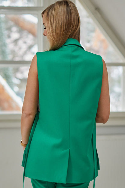 Back view of a model in a green La Aurora designer jacket vest, highlighting the elegant design and tailored fit in a bright indoor environment.