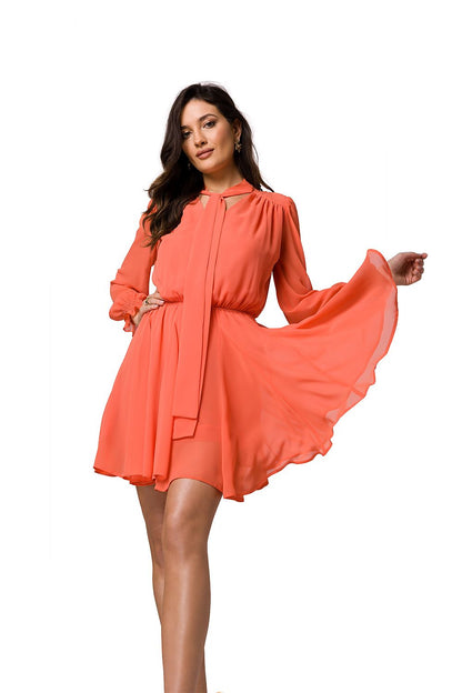 Stylish coral chiffon mini dress with a deep neckline and flared skirt by Makover, captured in a graceful twirl.