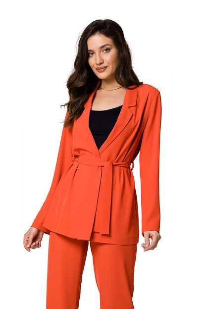 Model in a luxury flowing jacket in vibrant orange by Makover, elegantly styled over a black top, radiating a bold and sophisticated look.