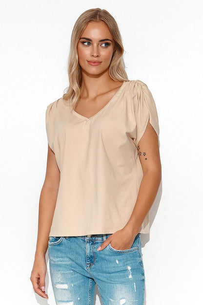 Stylish Makadamia oversized blouse in a soft beige colour with deep V-neck, elegantly posed by a model, perfect for transitional wardrobe styling.