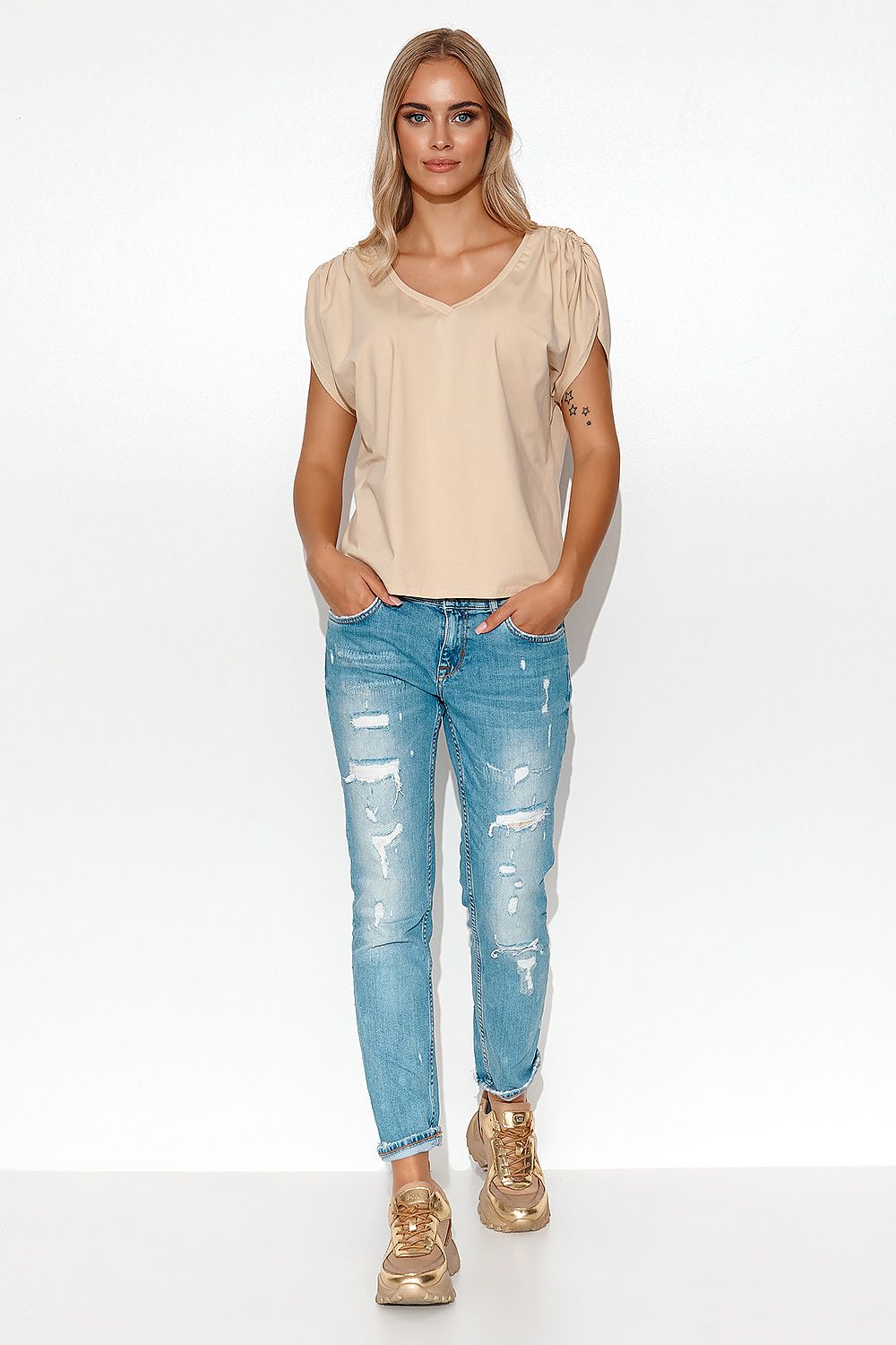 Elegant Makadamia oversize blouse with deep V-neck styled for women, paired with distressed blue jeans for a chic spring-summer look, showcasing comfort and luxury.