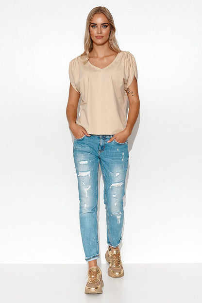 Elegant Makadamia oversize blouse with deep V-neck styled for women, paired with distressed blue jeans for a chic spring-summer look, showcasing comfort and luxury.