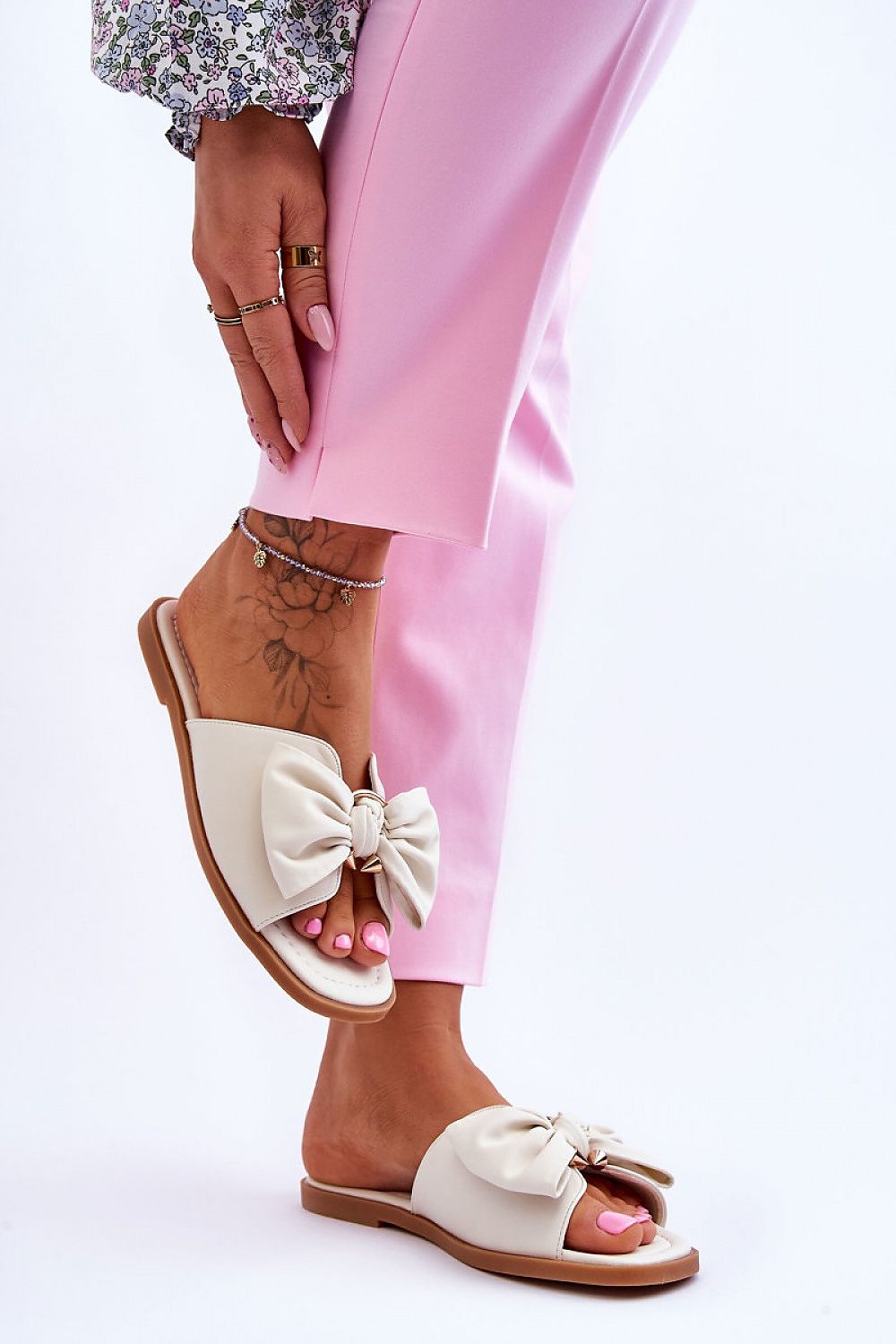 Close-up of a woman's foot in eco-leather flip-flops featuring a decorative bow, perfectly styled for summer, from Step in Style.