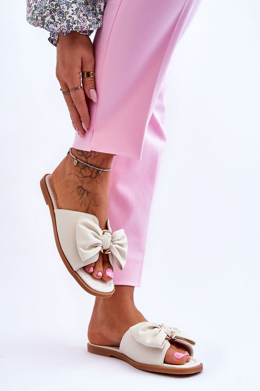 Close-up of a woman's foot in eco-leather flip-flops featuring a decorative bow, perfectly styled for summer, from Step in Style.