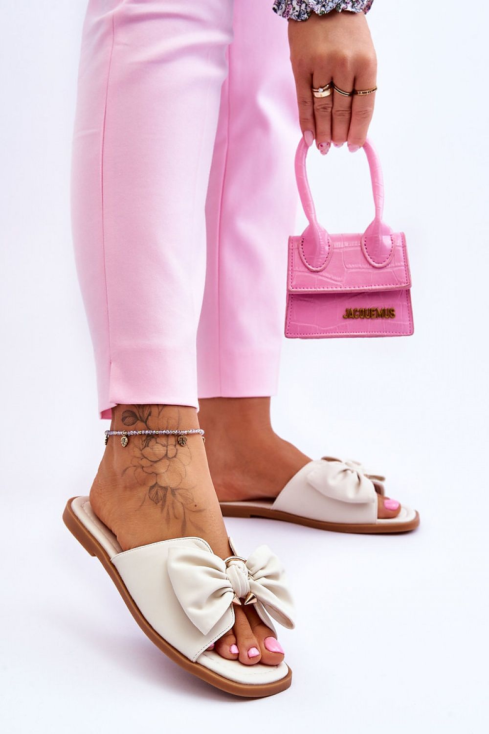 Fashionable eco-leather flip-flops with a large bow, showcasing a woman's foot holding a chic pink handbag, designed by Step in Style.