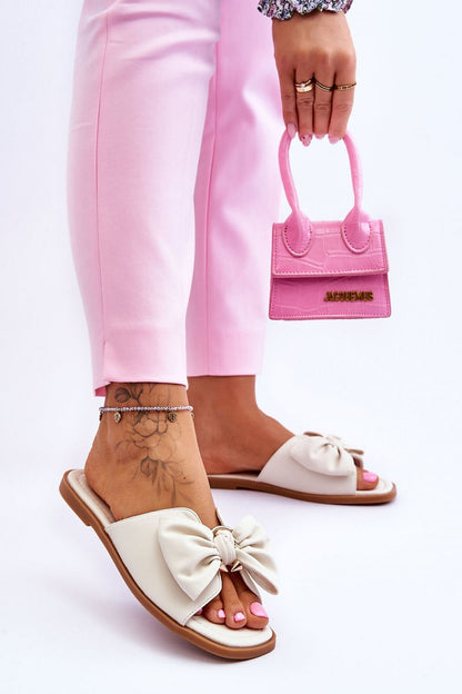 Fashionable eco-leather flip-flops with a large bow, showcasing a woman's foot holding a chic pink handbag, designed by Step in Style.