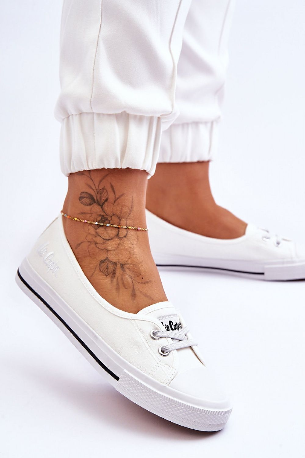 Stylish Lee Cooper women's low-top platform sneakers elegantly displayed, featuring elastic bands and a non-slip rubber sole, alongside a detailed floral ankle tattoo, exuding a modern luxury vibe.