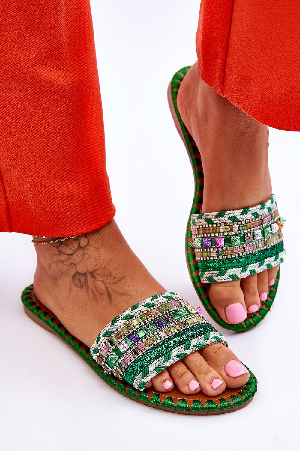 Trendy perspective showcasing luxury women's flip-flops adorned with rhinestones and glitter, designed by Step in Style, complemented by vibrant orange clothing.