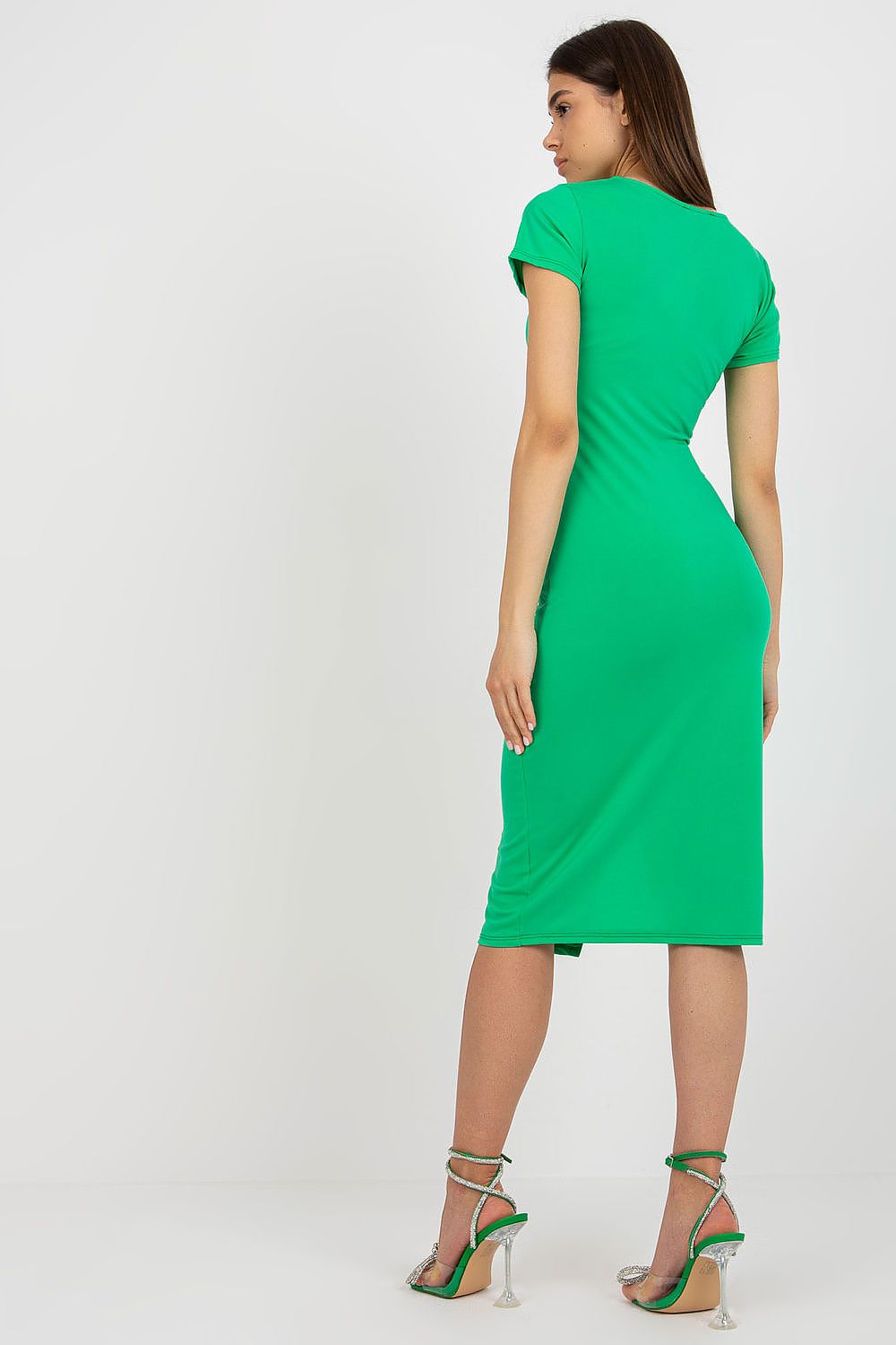Back view of a model in a stunning green fitted daydress by Italy Moda, highlighting the sophisticated tailoring and vibrant colour, complemented by stylish heels.