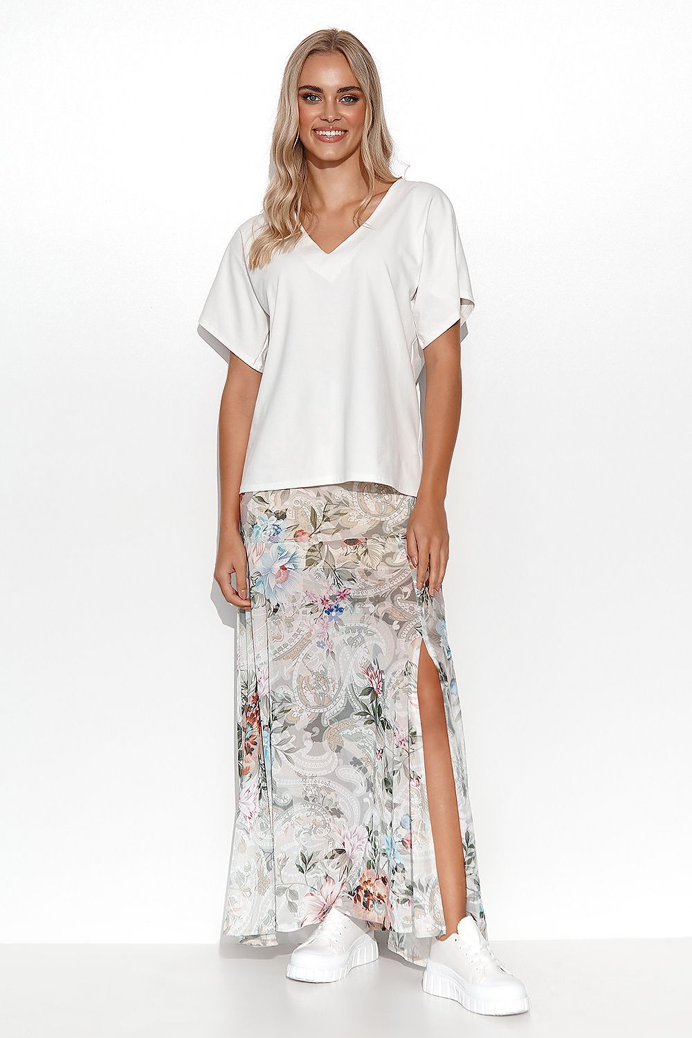 Stylish outfit featuring a woman in a white cotton blouse by Makadamia, paired with a floral maxi skirt, portraying a versatile and elegant spring look.